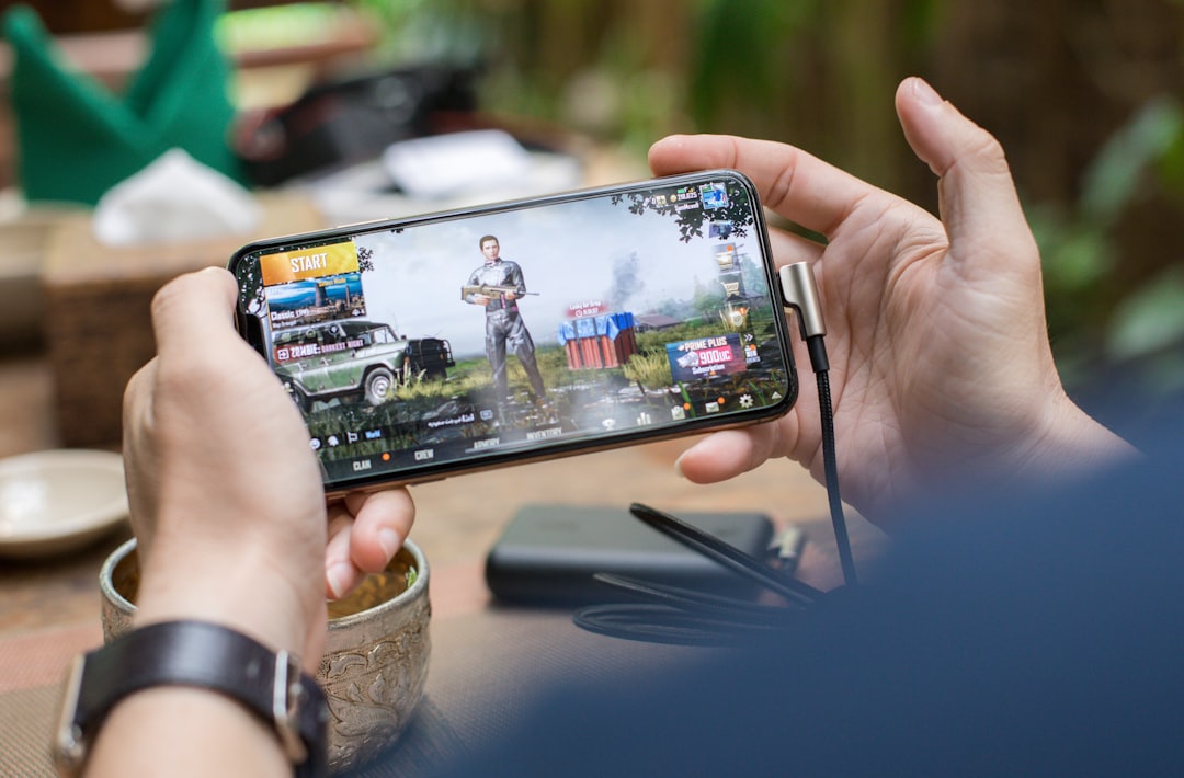 Tangan seseorang memainkan permainan di smartphone